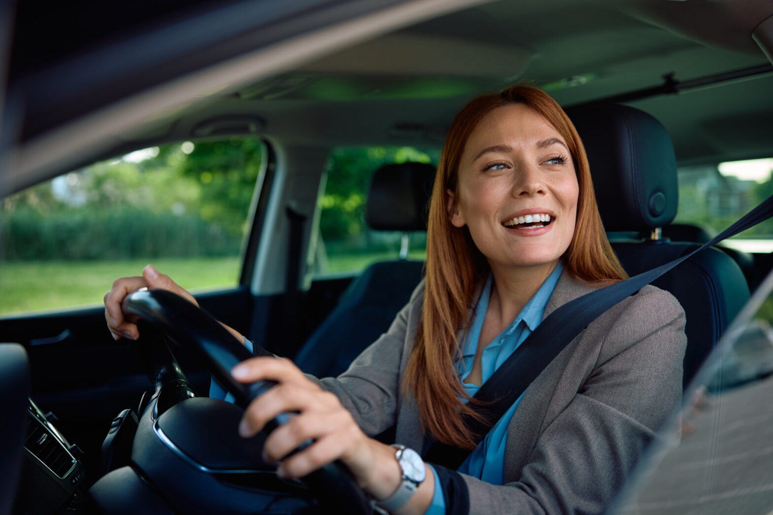 Woman driving a car and smiling confidently, representing financial control, independence, and navigating major life transitions.
