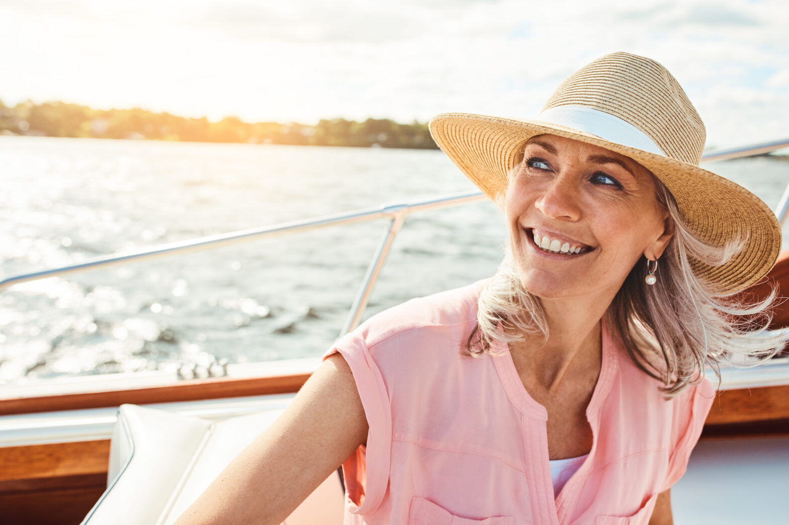 Woman smiling while seated on a boat, looking out over the water, representing confidence and planning for long-term care and future life stages.