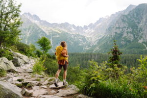 Woman sitting outdoors with a laptop, smiling thoughtfully, representing financial planning and independence after divorce later in life.