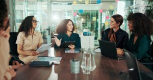 six women sitting in an office environment collaborating