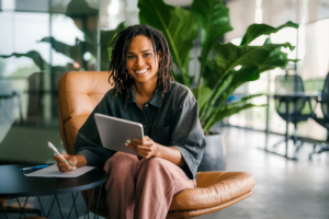 a wealth minded woman smiling with a tablet writing financial notes on a piece of paper