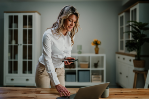 an independent woman working on her laptop and holding her phone