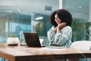 a woman sitting in a board room and got news about reaching a career milestone.